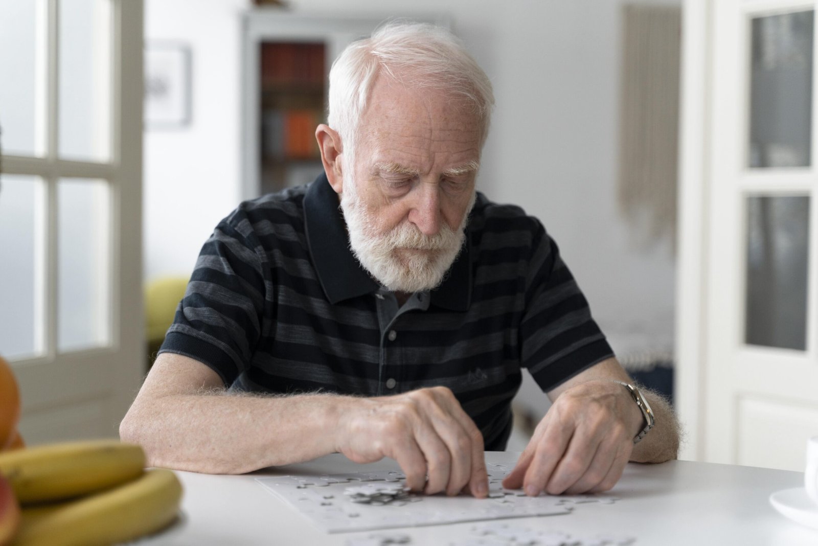Older man sitting at a table looking at a puzzle