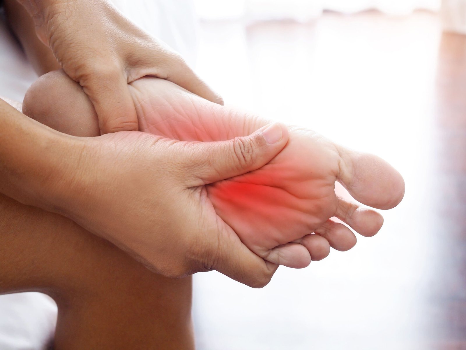 Hands holding a foot with pain highlighted in red