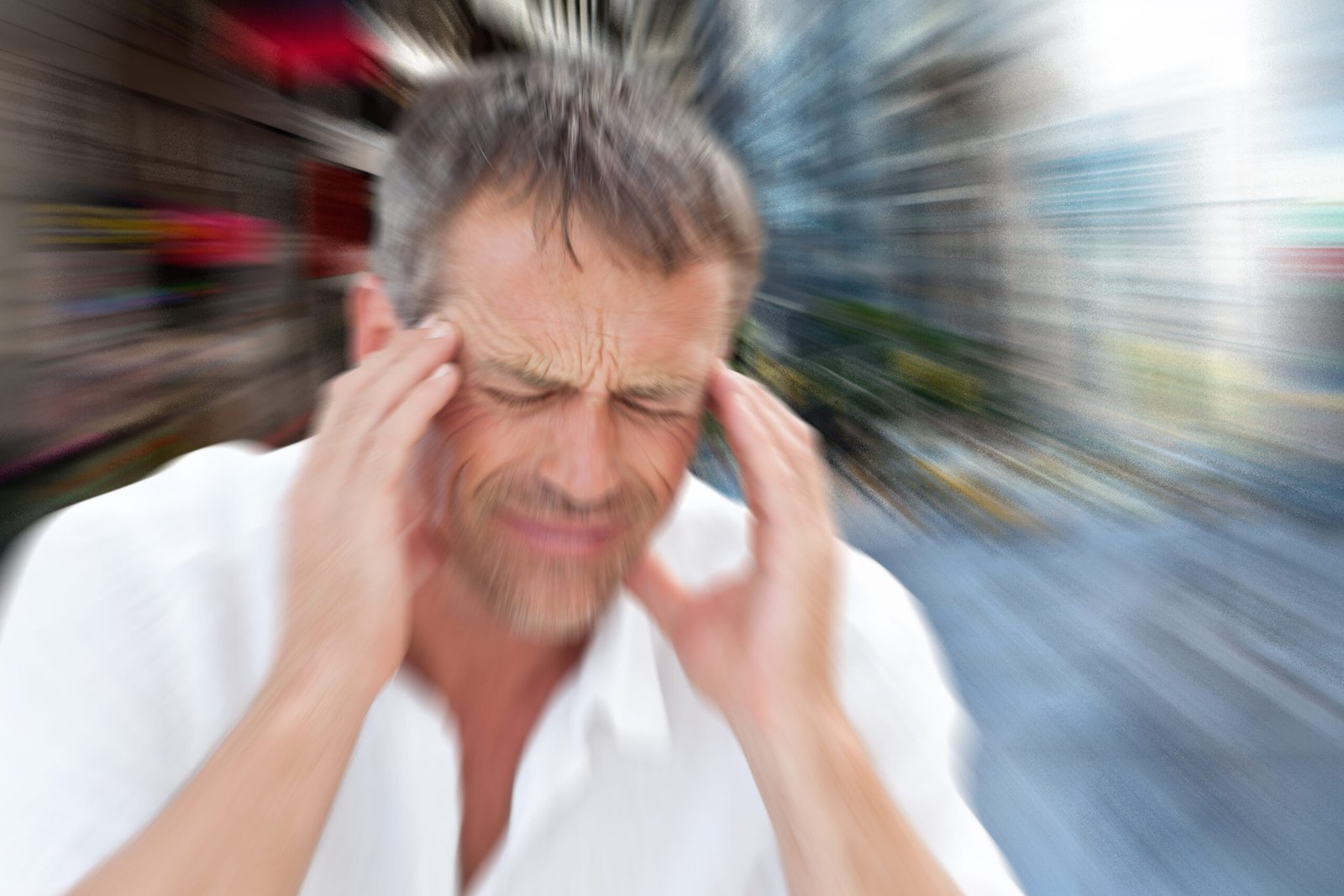 Man holding his head with a blurred background showing dizziness