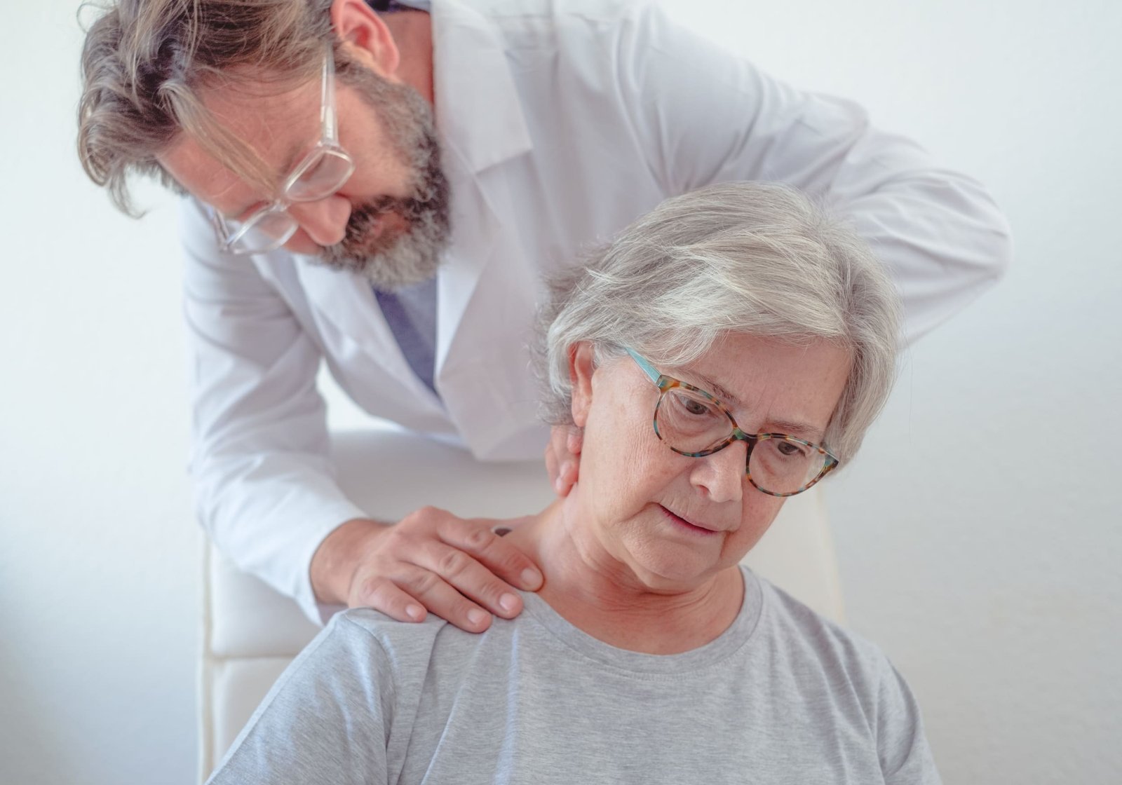Doctor examining an older woman's neck and shoulders