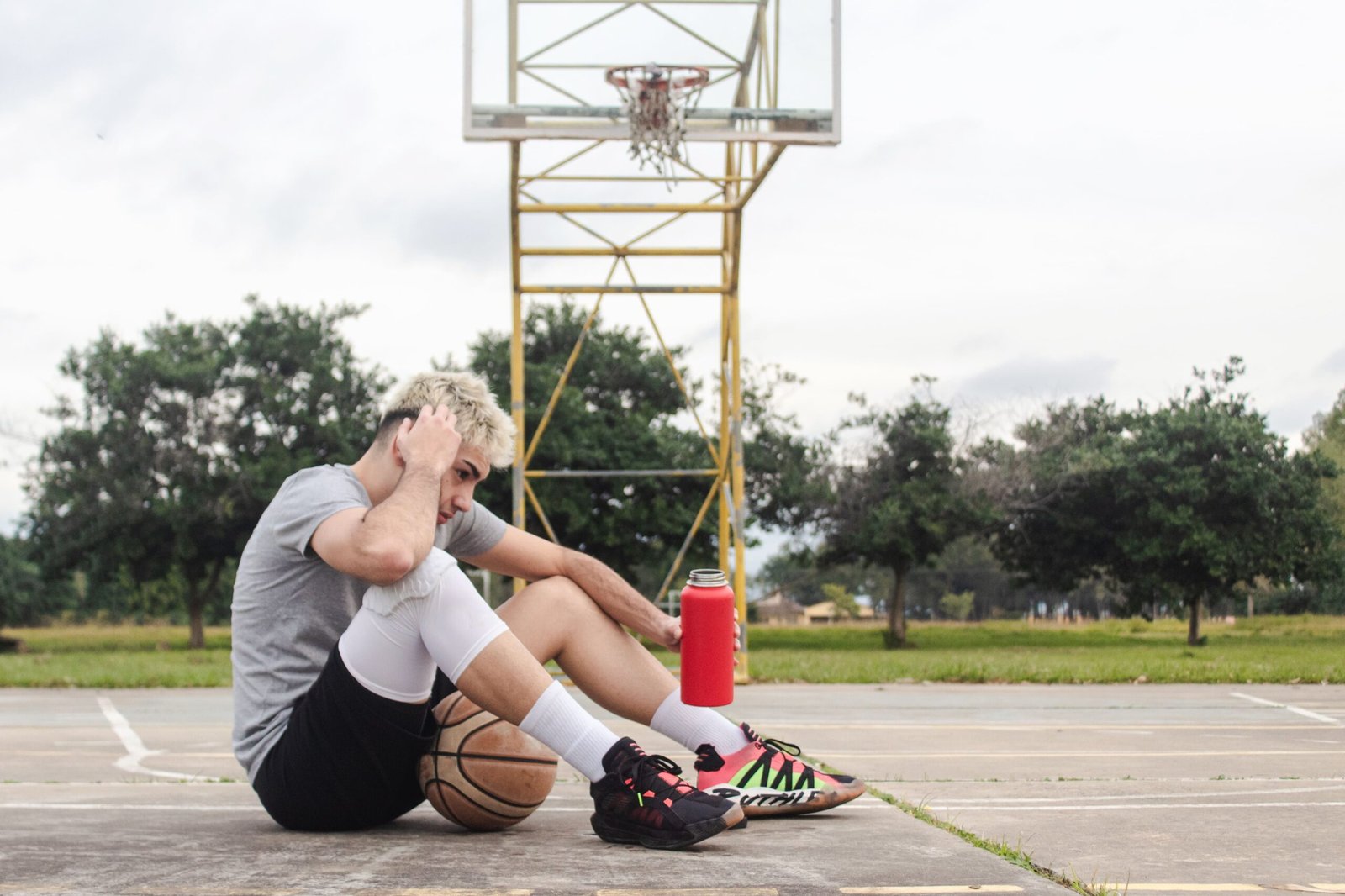 Tired young man sitting on a basketball court holding his head